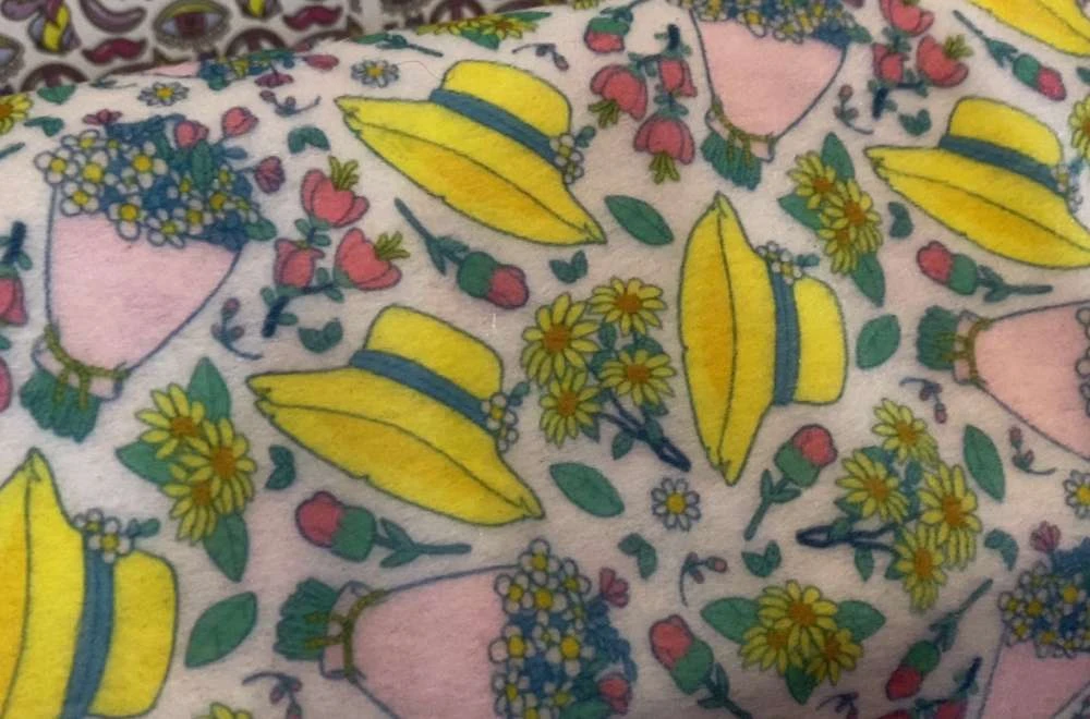 Hasil Cetak Tekstil Digital Dengan Motif Topi Kuning Dan Bunga Warna-Warni Yang Menunjukkan Perkembangan Teknologi Percetakan Di Allprint Indonesia 2026.